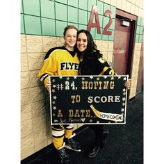 two people standing next to each other holding a sign