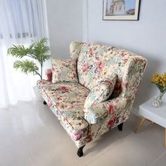 a living room filled with furniture and a plant on the floor next to a window