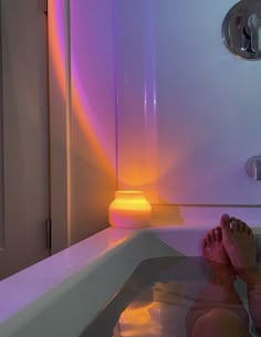 a person sitting in a bathtub with their feet up on the edge of the tub