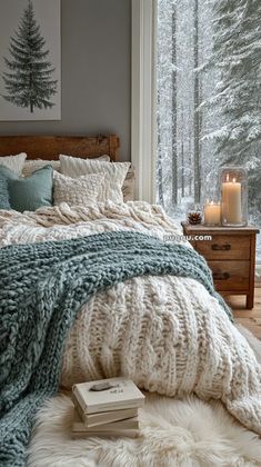 a bedroom with a large window and a bed covered in blankets, pillows and blankets