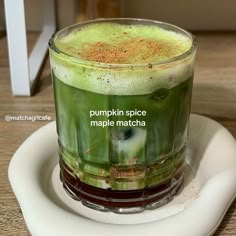 a cup filled with green liquid sitting on top of a white plate