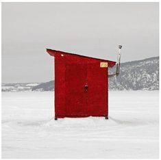 a red outhouse sitting on top of snow covered ground