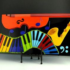 a colorful musical instrument with music notes painted on the front and sides, sitting on a black stand