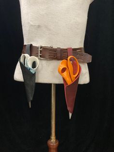 a white mannequin with two pairs of scissors on it's belt and some other items