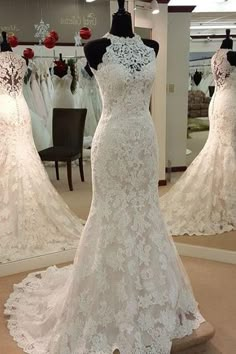 a white wedding dress on display in front of a mirror with mannequins