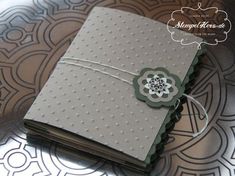 a close up of a small book on a metal tray with an ornamental pattern in the background