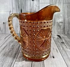 a brown glass pitcher sitting on top of a wooden table