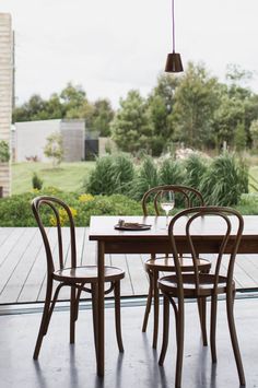 a table with four chairs and a wine glass on it in front of a window