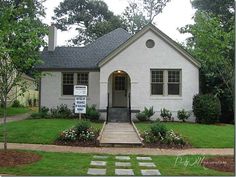 a house with a for sale sign in front of it and trees around the yard