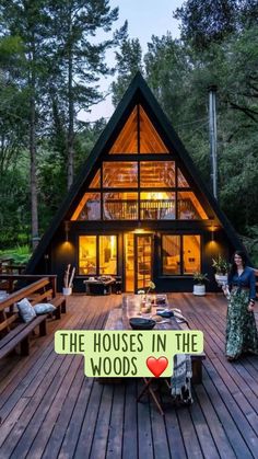 a woman is standing on the deck in front of a cabin style house with wood floors and large windows