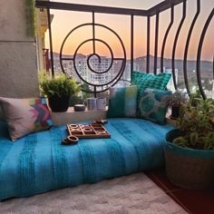 a blue couch sitting on top of a balcony next to potted plants and a window