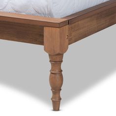 a wooden bed frame with white sheets on top of it and two legs at the bottom