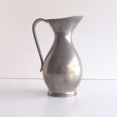 a silver pitcher sitting on top of a white table