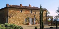 an old stone house with trees and bushes around it