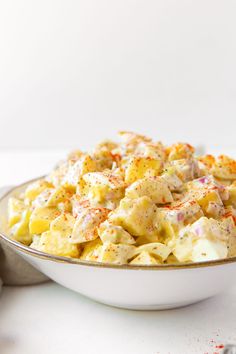 a white bowl filled with macaroni salad on top of a table next to utensils