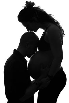 a man and woman kissing while standing next to each other with their hands on the belly