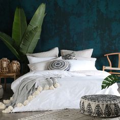 a bed with white sheets and pillows on top of it next to a green wall