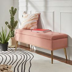 a pink bench sitting on top of a white rug next to a potted plant