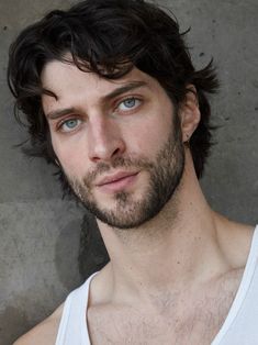 a close up of a person wearing a tank top and looking at the camera with a serious look on his face