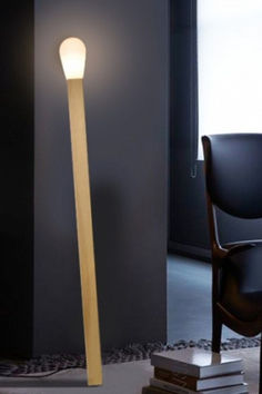 a lamp that is next to a chair and book on the floor in front of a window