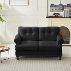 a black couch sitting next to a table with a potted plant on top of it