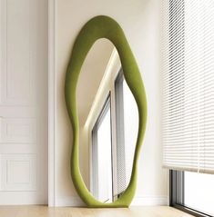 an oval shaped mirror in the corner of a room next to a window with blinds