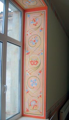 an open window in a room with flowers painted on the wall and below it is a decorative design