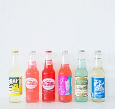 six different types of sodas lined up in a row on a white counter top