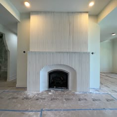 an empty room with a fire place in the center and white walls on both sides