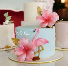 two cakes decorated with pink flowers and flamingos on top of each other, sitting on a table