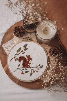 a wooden table topped with a white candle and embroidery