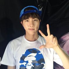 a young man is making the peace sign with his hand while wearing a blue hat