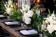 the table is set with white flowers and greenery