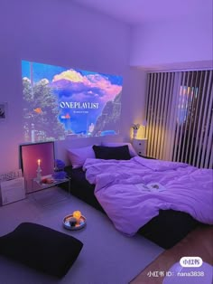 there is a bed with purple sheets and pillows on the floor in front of a large screen