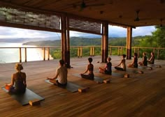 a group of people sitting on yoga mats in the middle of a wooden floored area