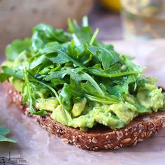 an open face sandwich with avocado and spinach on toasted rye bread