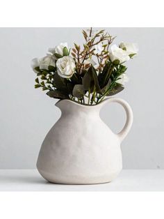 a white vase filled with flowers on top of a table