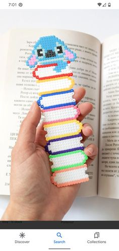 a hand holding an open book with a small toy in it's middle and the pages are lined up