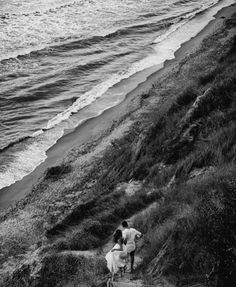 two people are walking up the hill towards the ocean