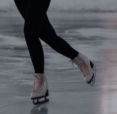 a person skating on an ice rink with their feet in the air and one leg up