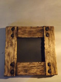 an old wooden frame with metal rivets is hanging on the wall in front of a white wall