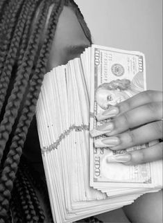 a woman with dreadlocks holding money in front of her face and looking at the camera