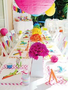 the table is set up with colorful flowers and paper napkins on top of it