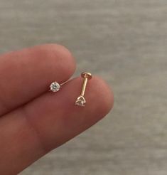 a person holding a tiny diamond earring in their hand