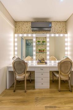 two chairs sit in front of a vanity with lights on the wall and below it