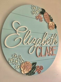 a sign that says elizabeth care with flowers and leaves on the bottom, in front of a white wall