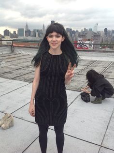 a woman standing on top of a roof with her hands in the air and wearing black tights