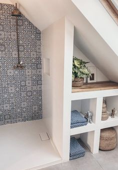 an attic bathroom with blue and white tiles on the shower wall, shelving unit