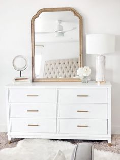 a white dresser with a large mirror above it