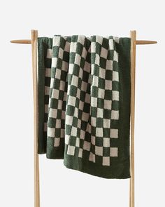 a black and white checkered towel hanging on a clothes rack with two wooden pegs